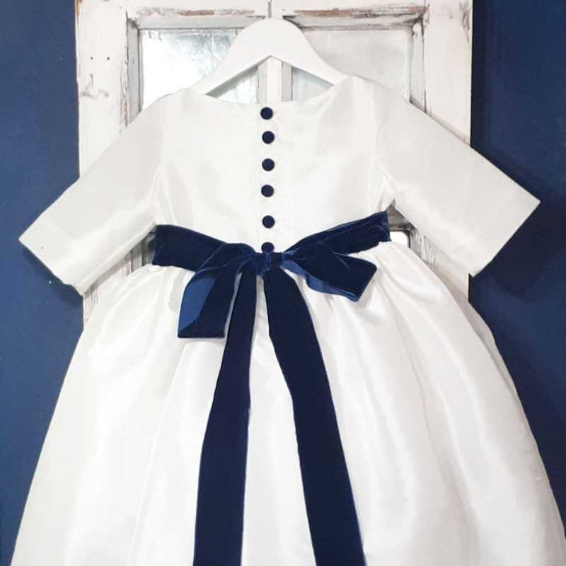 White flower girl dress with nav blue velvet sash and covered buttons with 3/4 length sleeves by Little Eglantine